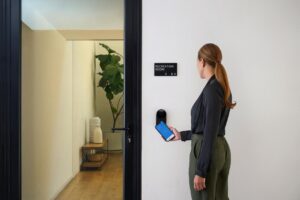 Woman walking into rec room using phone and R reader by latch 